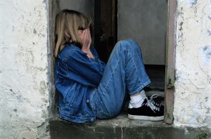 Child sititng with hands in hands waering all denim