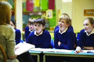 Row of school children in row listening to teacher