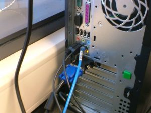 The back of a computer with several ports and wires sticking out.