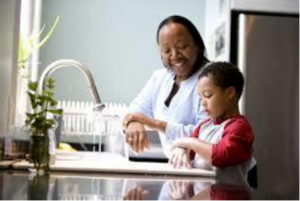 A mother helping her son wash his hands.