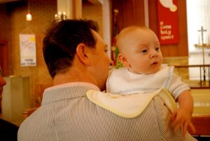 A father holding his baby with a cloth protecting his shoulder from spit-up.