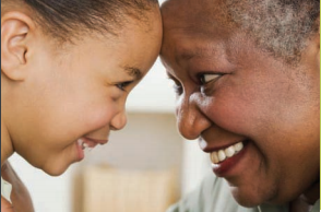 A child and older adult smile at each other.