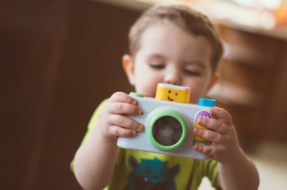 Toddler playing with a toy camera.