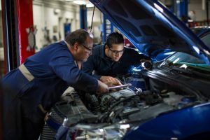 student and faculty working on a car , for an automotive engineering project.
