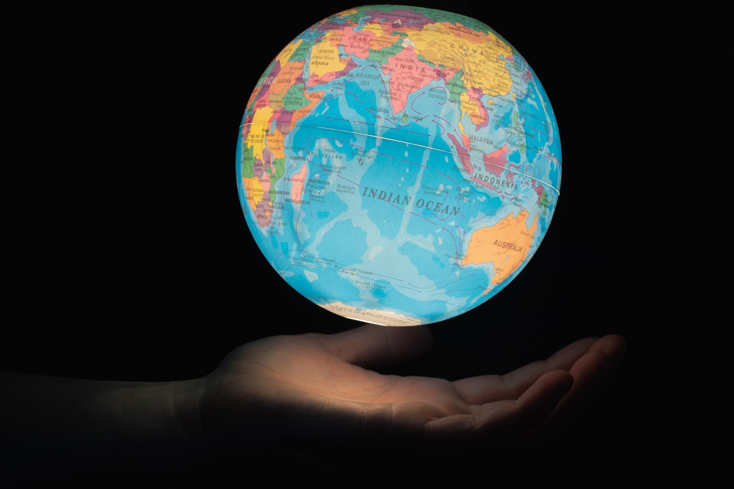 Globe light floating above hand with the Indian ocean facing the camera.