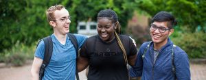 diverse group of students outside smiling with their arms around each other.