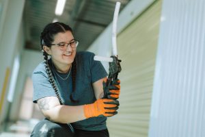 student smiling while holding plumbing tools