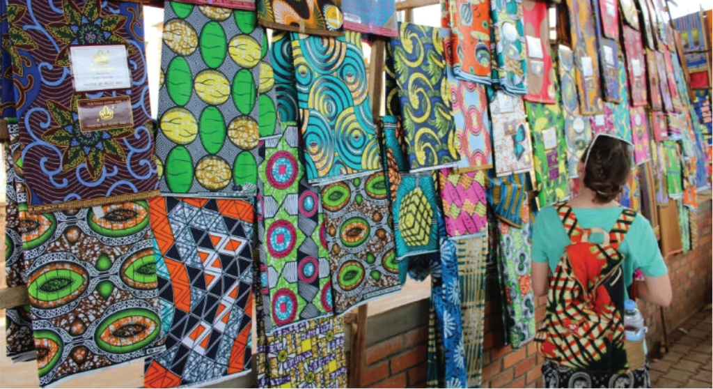 A wall of textile fabric samples are on display. A woman is in the foreground viewing them.