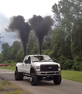 Photo of Ford F-450 with two plumes of thick black smoke shooting up from the rear end.