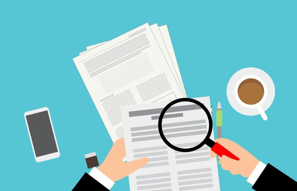 Someone inspecting a document with a magnifying glass
