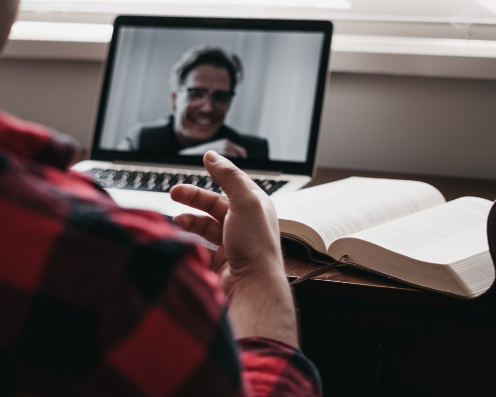 A person is seen talking to someone on a laptop.