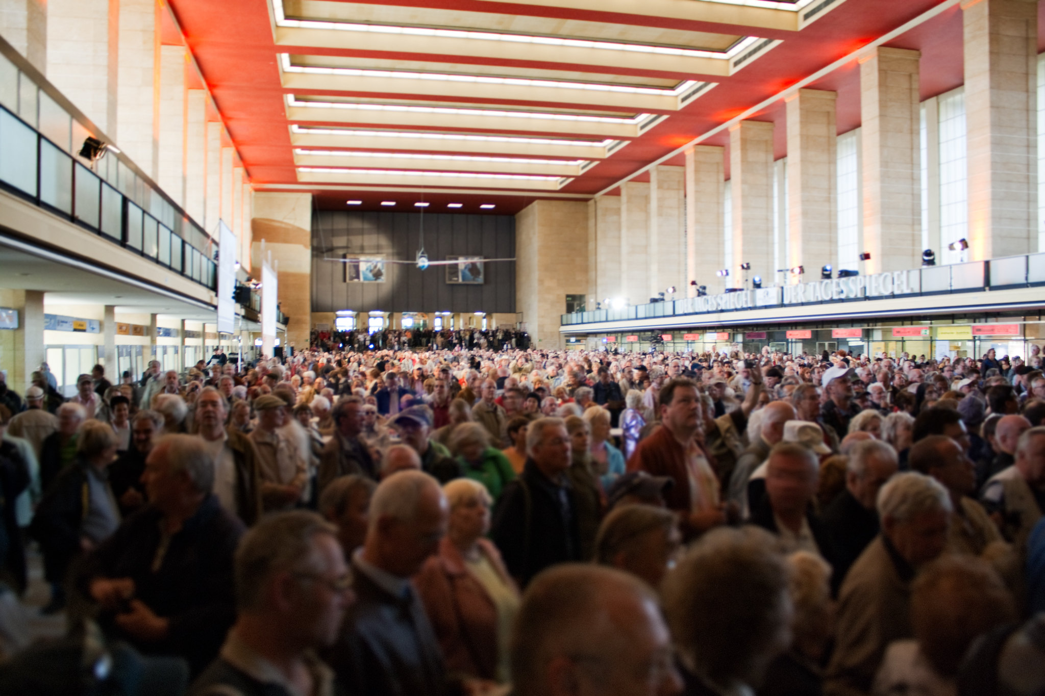 A huge crowd in a lobby-like area with a high ceiling.