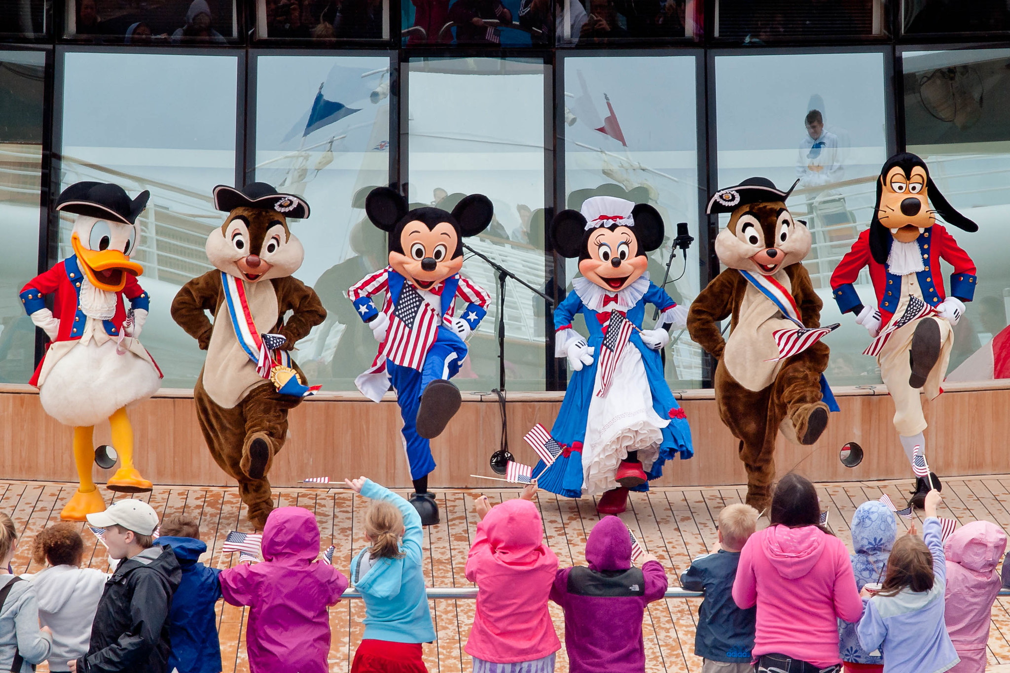 People dressed in classic Disney character costumes perform for a crowd of children. People dressed in classic Disney character costumes perform for a crowd of children.