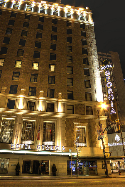 The front of a historic hotel at night. A neon sign says "Hotel Georgia."