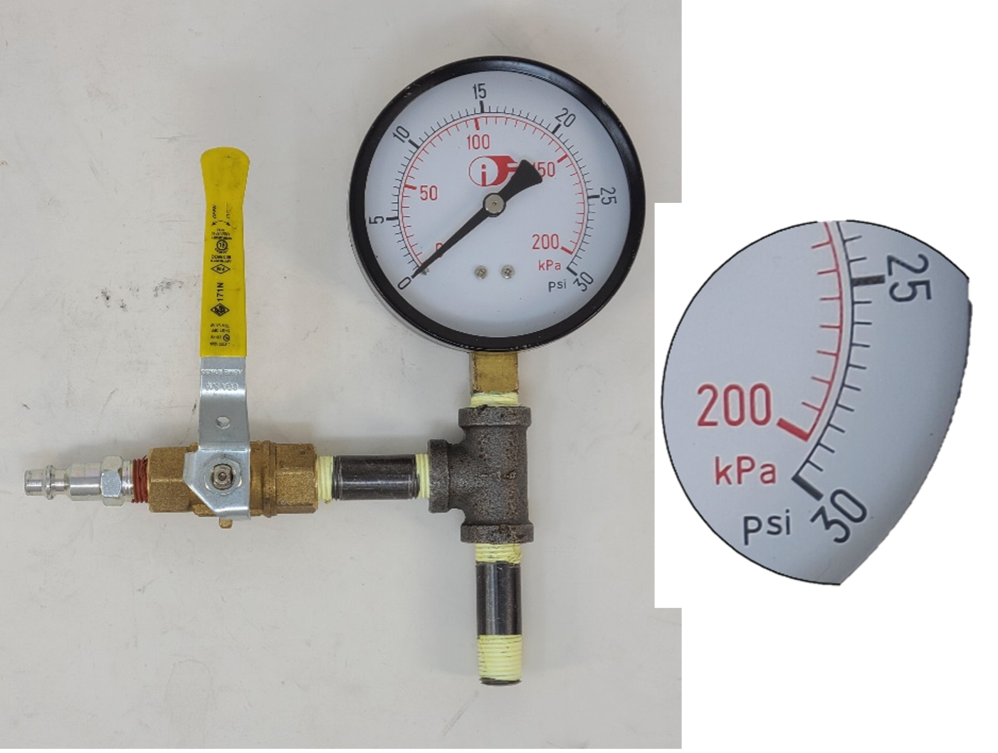 A pressure test assembly with a gauge. It highlights the end of the gauge, which ends at 200 kPa and 30 psi.