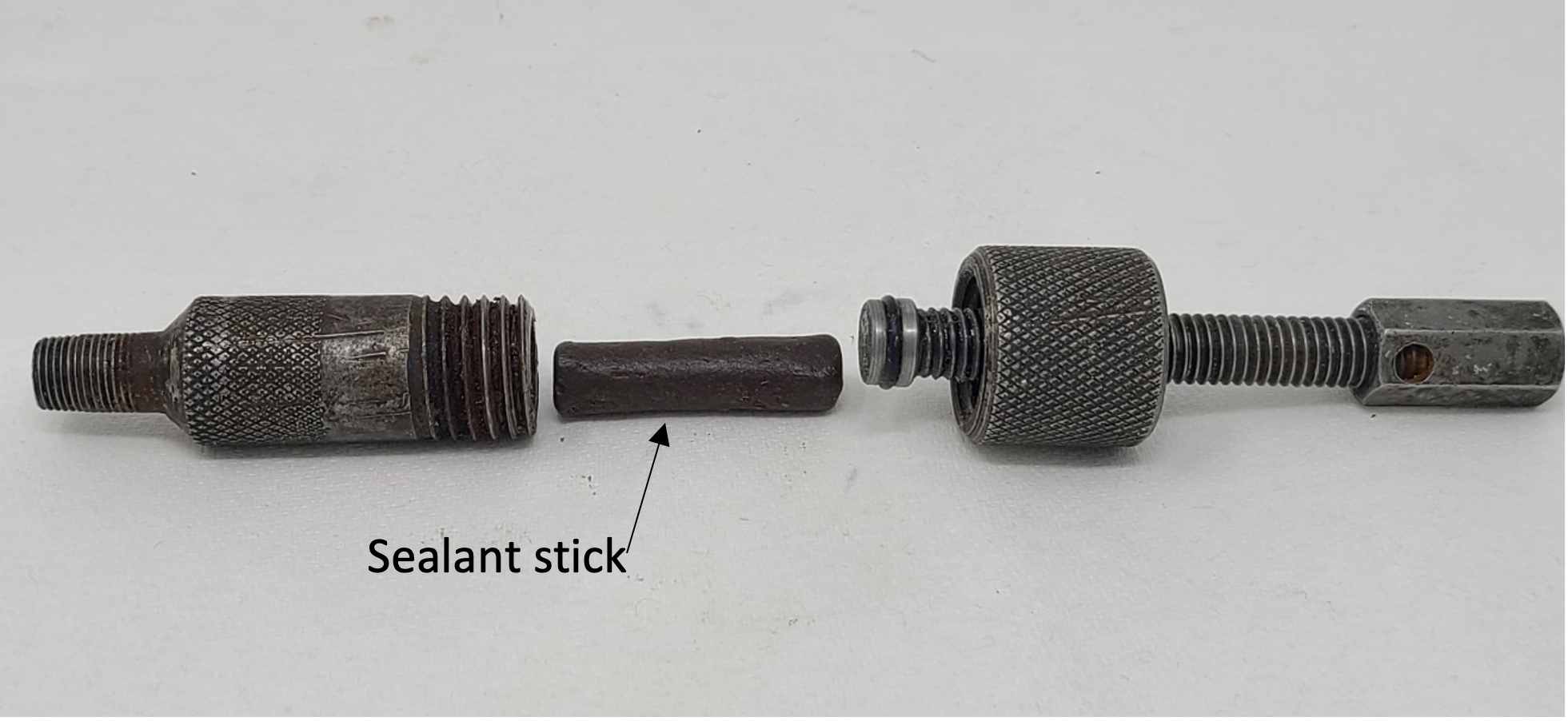 A screw injection tool disassembled to show the sealant stick.